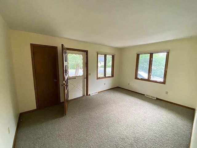 empty room featuring visible vents, baseboards, and carpet floors