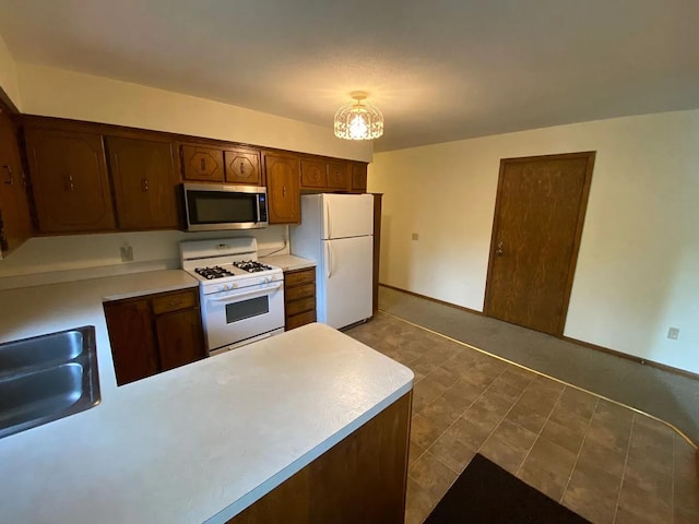 kitchen with white appliances, light countertops, and baseboards