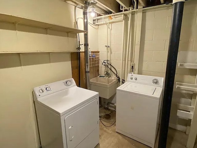 washroom with a sink, concrete block wall, separate washer and dryer, and laundry area