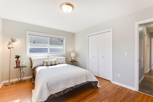 bedroom featuring light wood finished floors, a closet, and baseboards