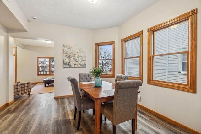 dining space with a textured ceiling, wood finished floors, and baseboards