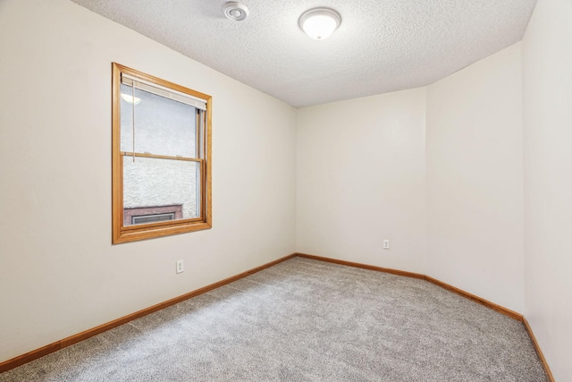 carpeted empty room featuring a textured ceiling and baseboards