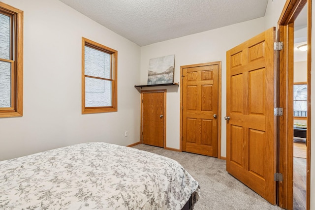 bedroom with a textured ceiling, carpet, and baseboards