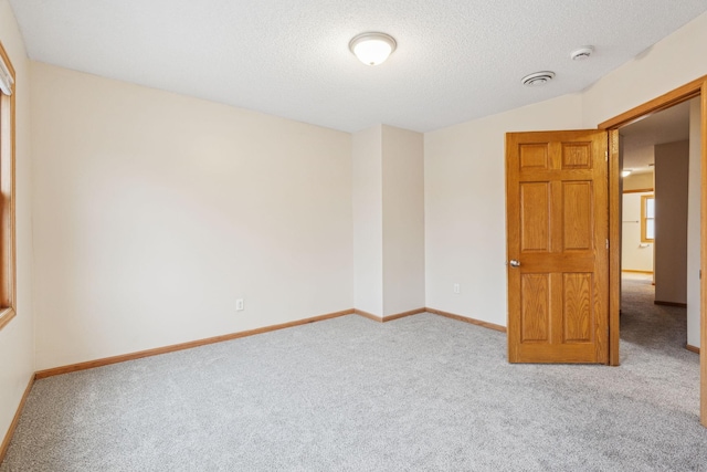 carpeted empty room with a textured ceiling and baseboards