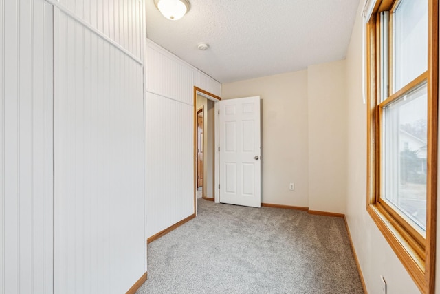 empty room with carpet floors, baseboards, and a textured ceiling