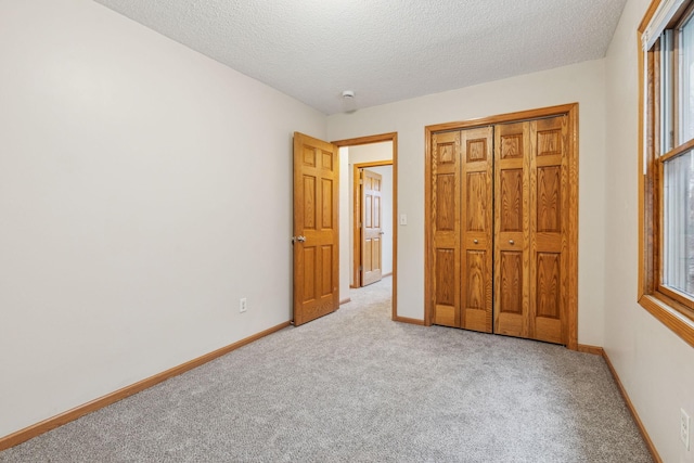 unfurnished bedroom featuring a closet, a textured ceiling, baseboards, and carpet flooring