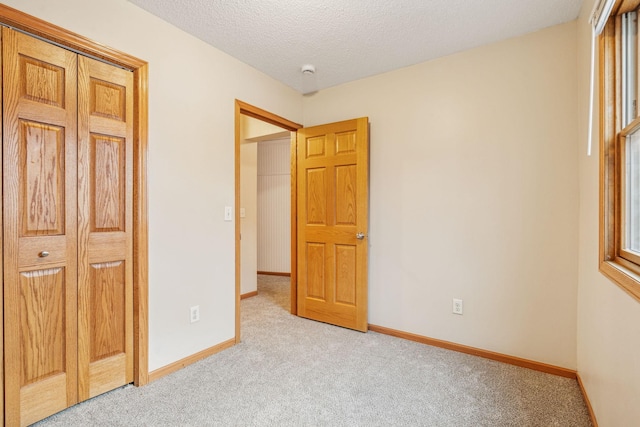 unfurnished bedroom featuring a textured ceiling, carpet, and baseboards