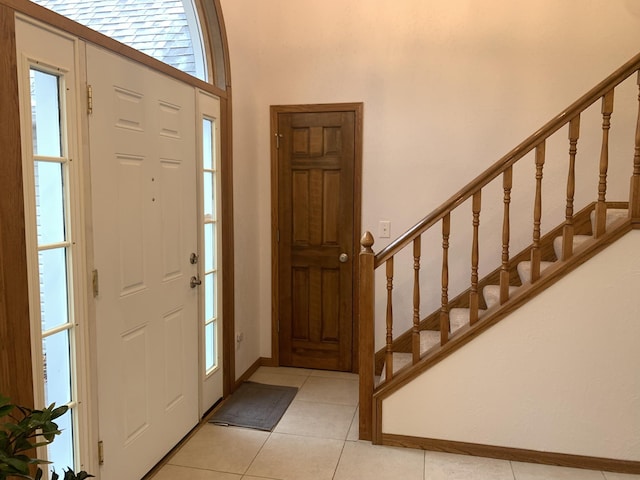 foyer entrance featuring stairway, light tile patterned floors, and baseboards