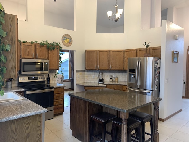 kitchen with stainless steel appliances, a high ceiling, a breakfast bar, and brown cabinetry