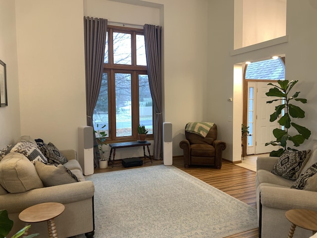 living room featuring baseboards, a towering ceiling, and wood finished floors