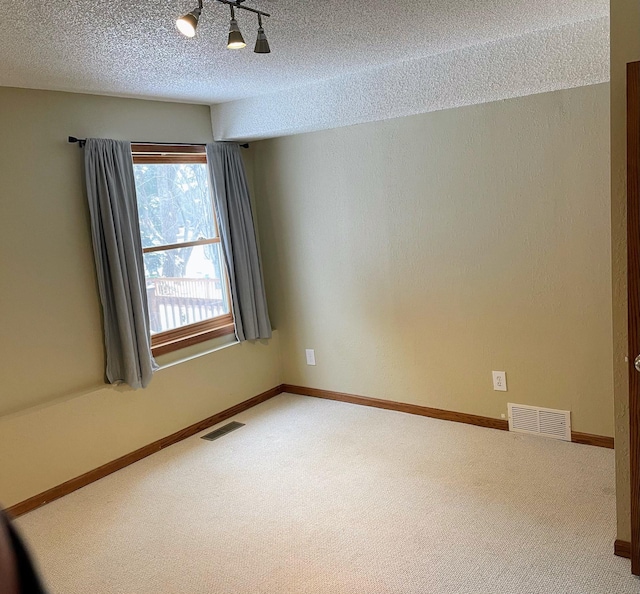 unfurnished room featuring visible vents, baseboards, a textured ceiling, and carpet