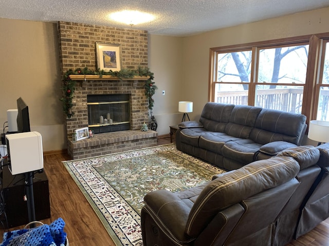 living area featuring a fireplace, a textured ceiling, baseboards, and wood finished floors