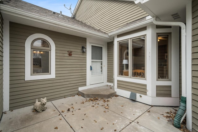 property entrance with roof with shingles and visible vents