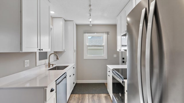 kitchen featuring appliances with stainless steel finishes, a sink, and white cabinets