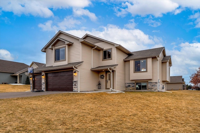 view of front of property with driveway, stone siding, an attached garage, and a front lawn