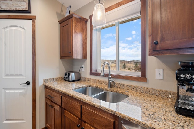 kitchen with a sink, light stone countertops, and brown cabinets