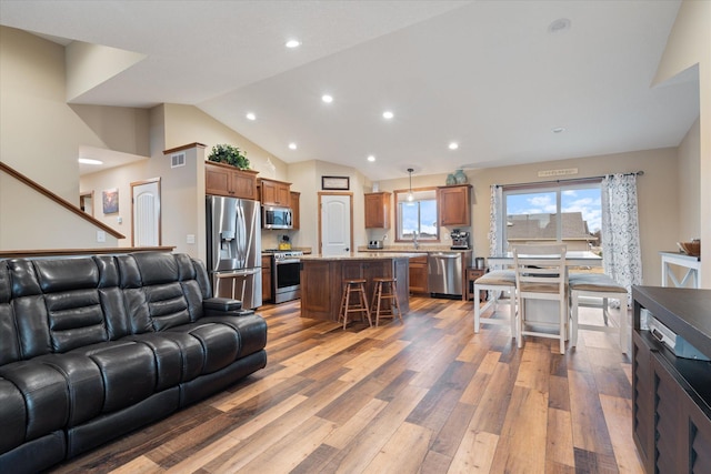 living area featuring recessed lighting, visible vents, vaulted ceiling, and wood finished floors