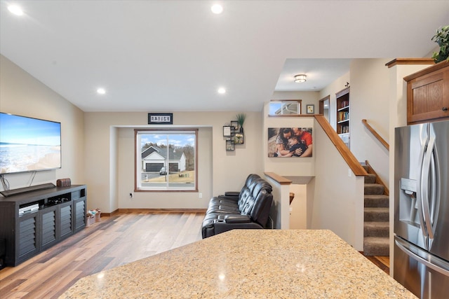 kitchen featuring a healthy amount of sunlight, light wood-style floors, light stone countertops, and stainless steel fridge with ice dispenser