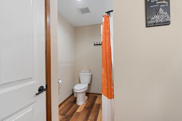 bathroom with toilet, wood finished floors, visible vents, and baseboards