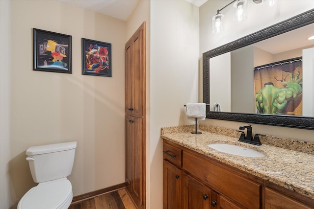 bathroom with wood finished floors, vanity, toilet, and baseboards