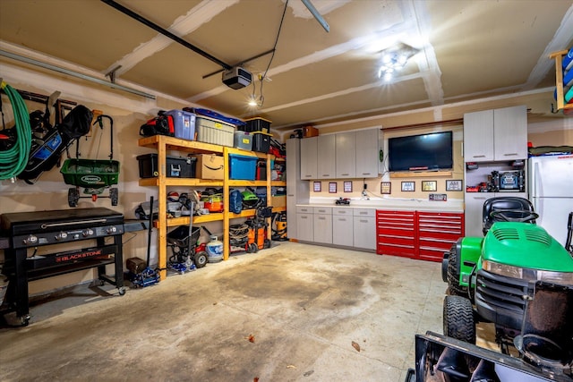 garage with freestanding refrigerator, a workshop area, and a garage door opener