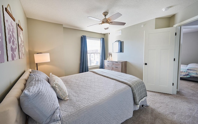 bedroom featuring a ceiling fan, light carpet, and a textured ceiling