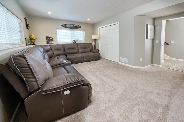 living area featuring baseboards, visible vents, a wealth of natural light, and light colored carpet