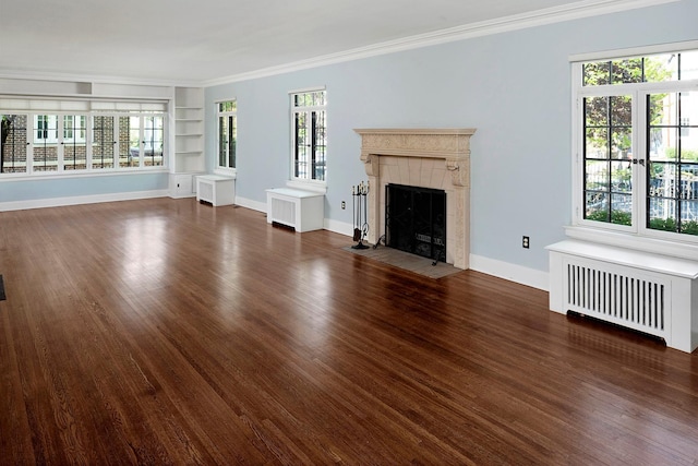 unfurnished living room with baseboards, radiator, dark wood-style floors, crown molding, and a fireplace