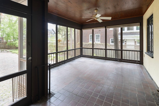 unfurnished sunroom with a ceiling fan, wooden ceiling, and plenty of natural light