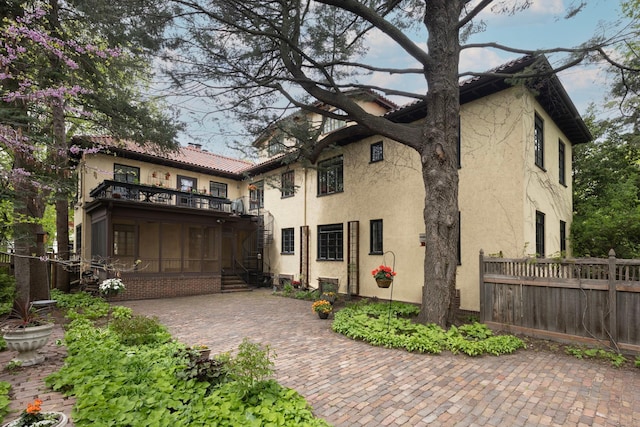 view of front of house with a balcony, fence, a patio, and stucco siding