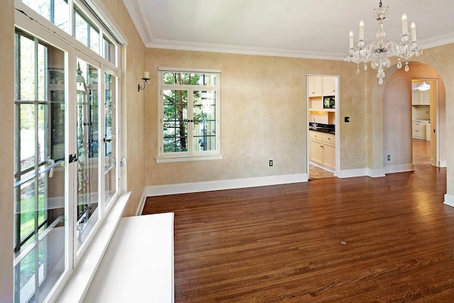 interior space featuring arched walkways, dark wood-type flooring, ornamental molding, a sink, and baseboards