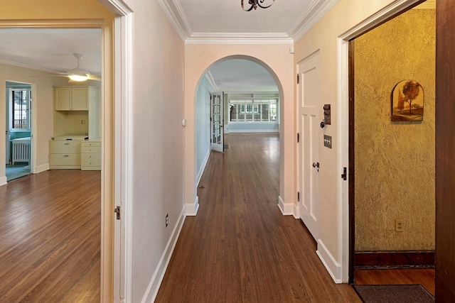 hallway with arched walkways, dark wood-type flooring, radiator heating unit, and crown molding