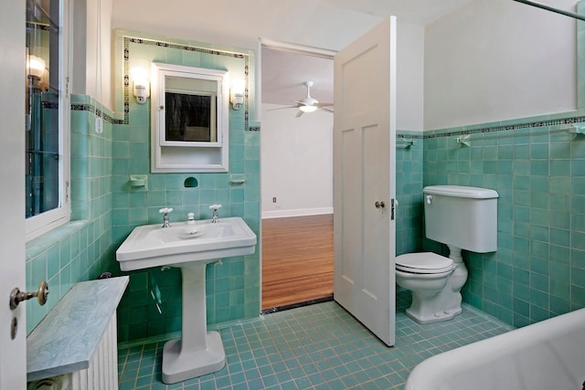 bathroom featuring toilet, ceiling fan, tile walls, and tile patterned floors