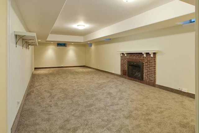 finished below grade area with baseboards, carpet, and a brick fireplace