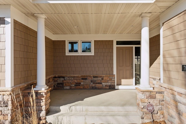 doorway to property featuring covered porch and stone siding