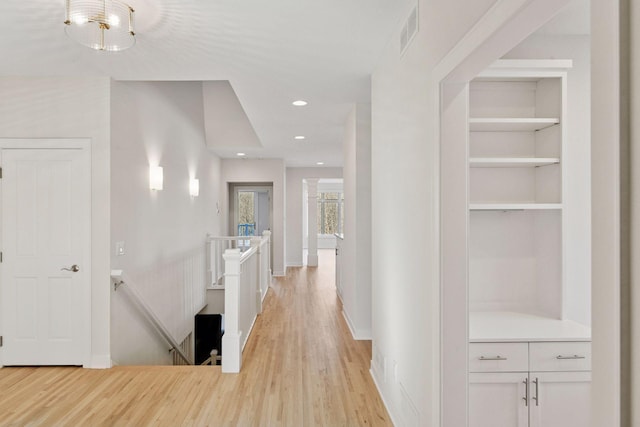 hall with recessed lighting, visible vents, an upstairs landing, built in features, and light wood finished floors