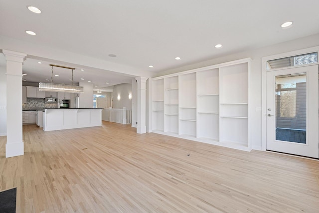 unfurnished living room featuring light wood-type flooring, ornate columns, and recessed lighting