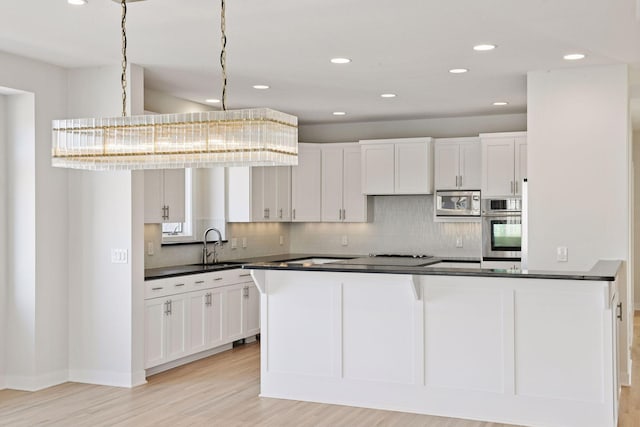 kitchen featuring decorative backsplash, dark countertops, stainless steel appliances, white cabinetry, and a sink