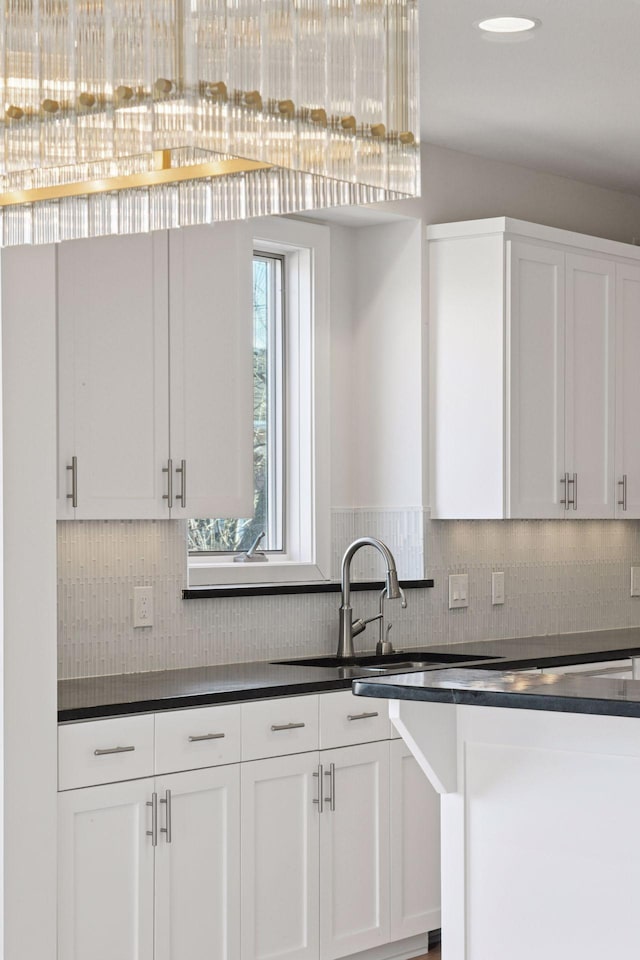 kitchen with dark countertops, white cabinets, and decorative backsplash