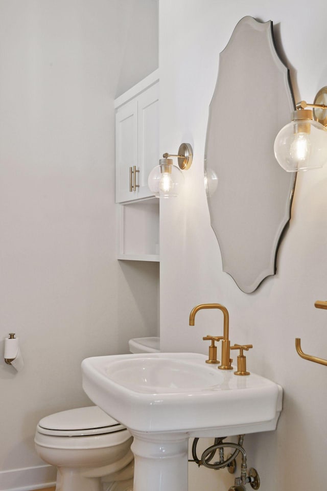 bathroom with a sink, toilet, and baseboards