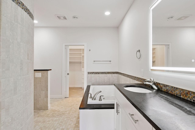 full bathroom featuring a garden tub, a walk in closet, tile walls, and recessed lighting