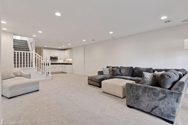 living area with recessed lighting, light colored carpet, baseboards, and stairs