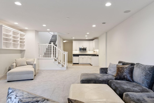 living room featuring recessed lighting, light colored carpet, baseboards, and stairs