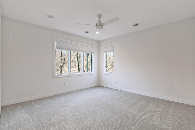 unfurnished room with carpet floors, visible vents, ceiling fan, and baseboards