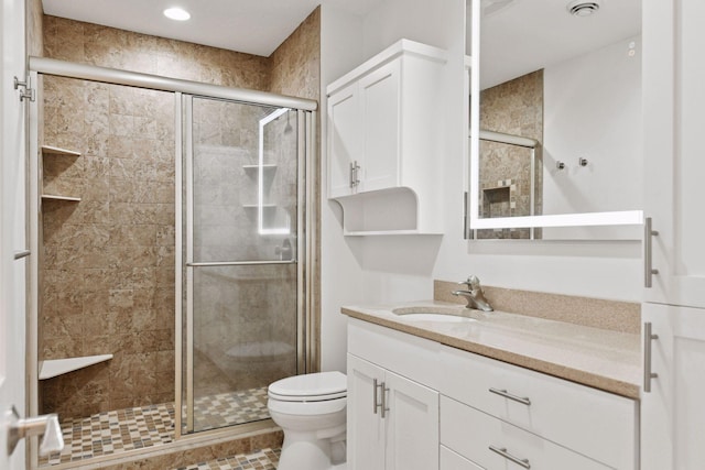 full bathroom featuring a stall shower, vanity, and toilet