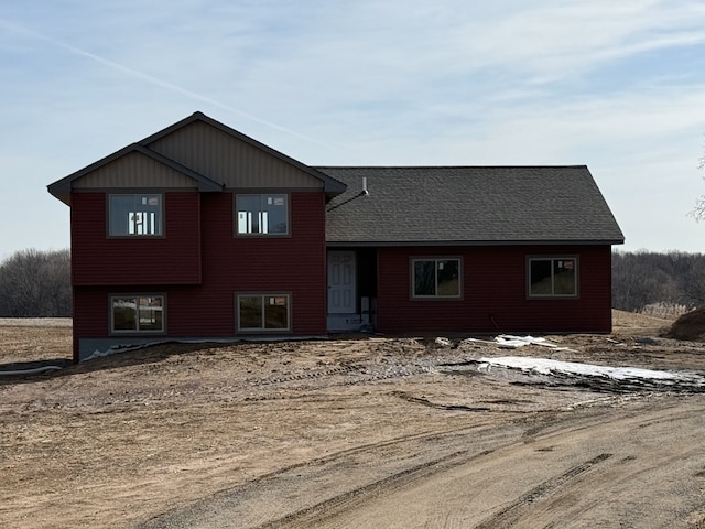 split level home with roof with shingles