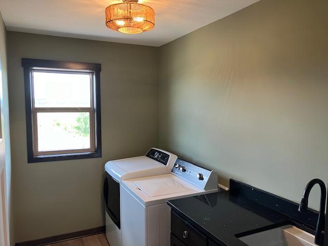 laundry room featuring washing machine and dryer, wood finished floors, and a sink