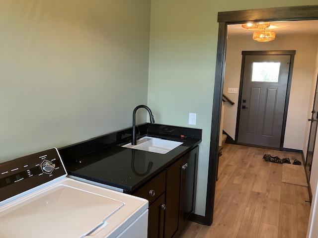 laundry area featuring washer and clothes dryer, cabinet space, light wood-type flooring, and a sink