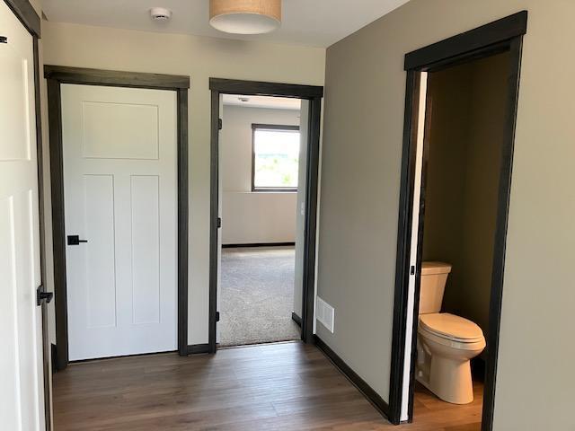 hall featuring visible vents, baseboards, and wood finished floors