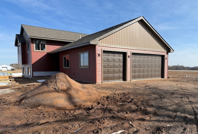 view of property exterior featuring a detached garage and roof with shingles